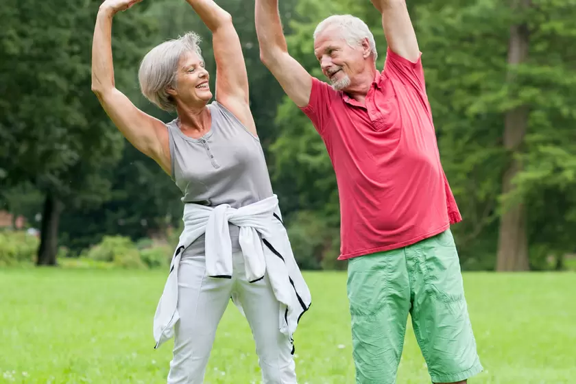 two older adults stretching in a park